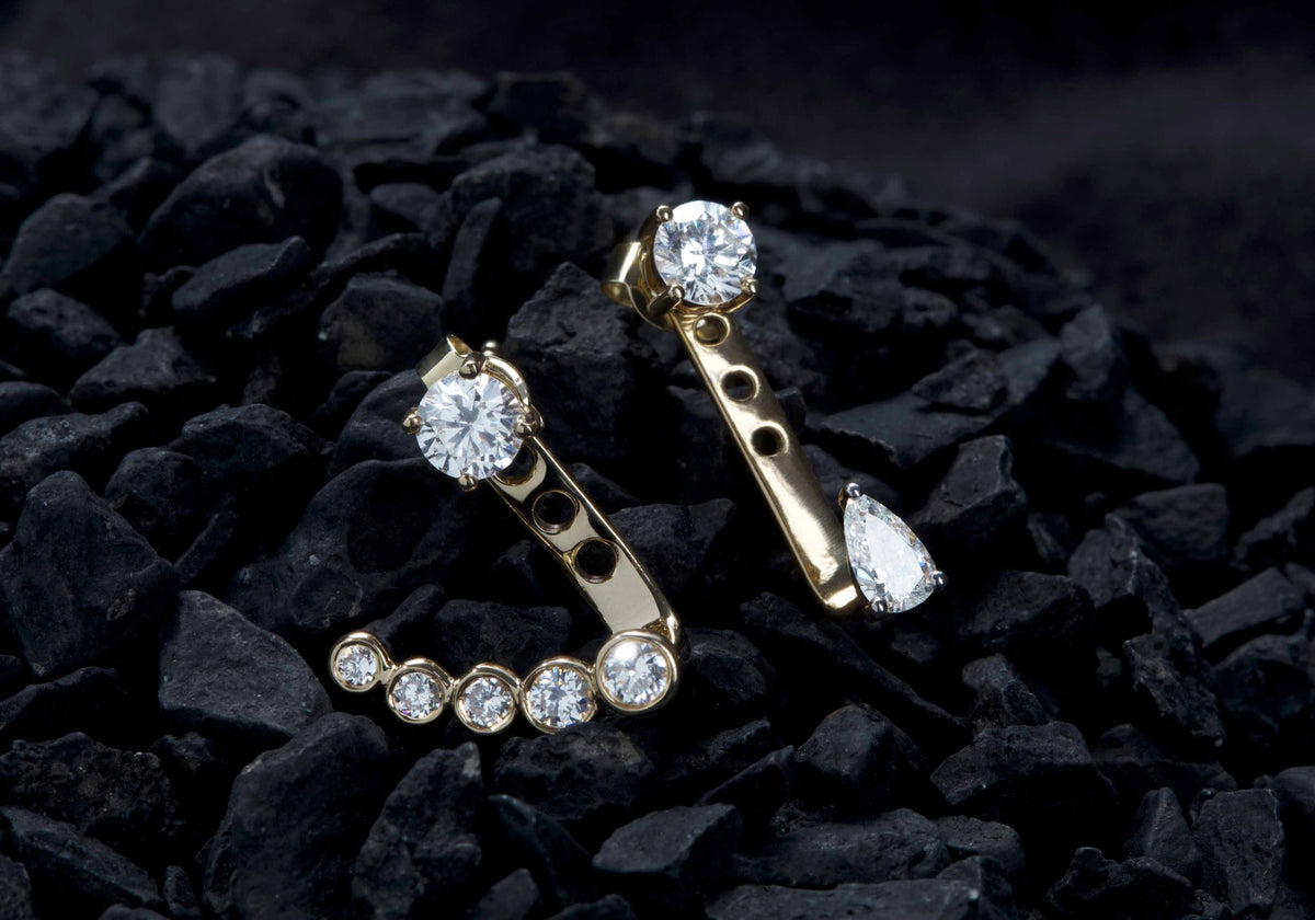 Gold earrings with diamond stones on a dark textured surface