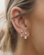 Close-up of an ear wearing multiple diamond earrings with a blurred background