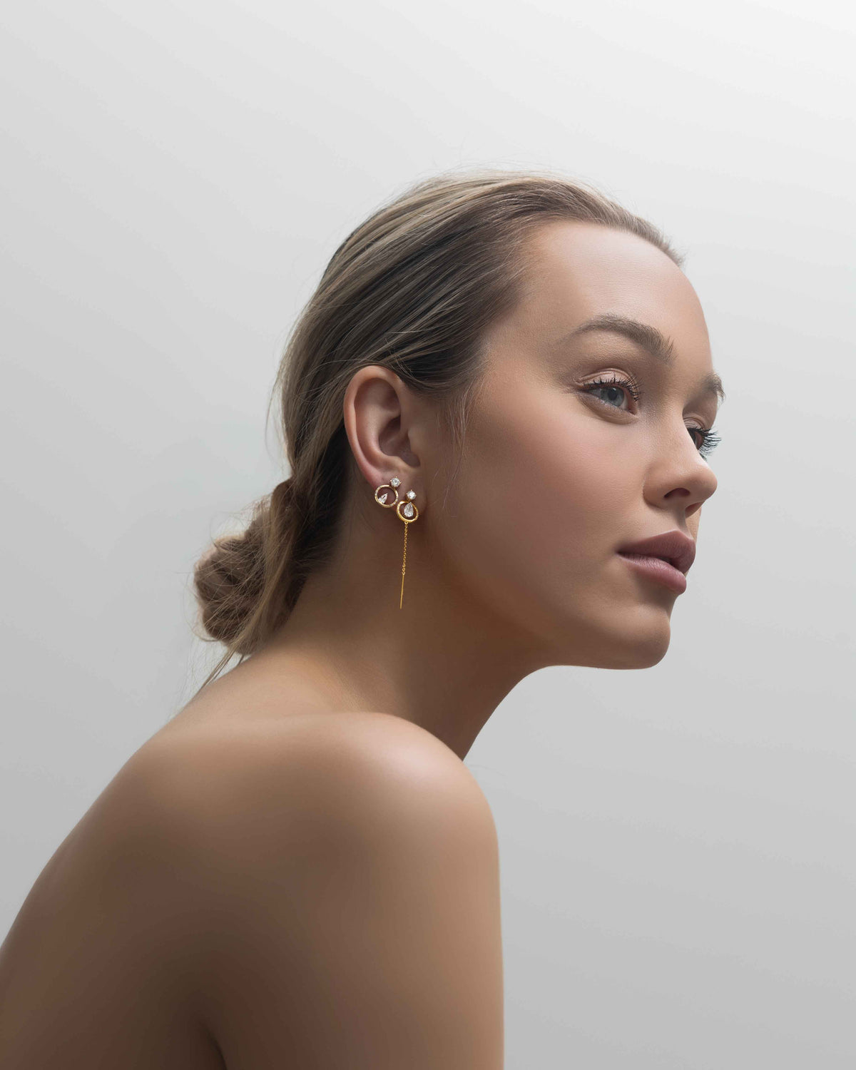 Woman wearing gold earrings against a plain background